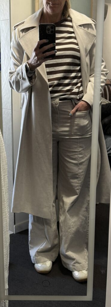 Outfit consisting of white trench, brown striped shirt, white corduroy pants.