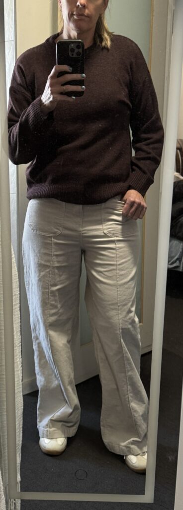 Outfit consisting of brown sweater, white corduroy pants.