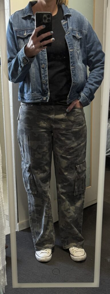 Outfit consisting of denim jacket, black shirt, camo pants.