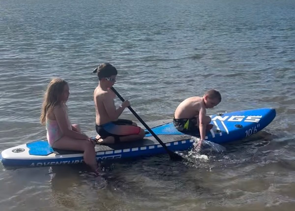 Kids paddling on an inflatable stand-up paddleboard at Cotton Tree beach, Sunshine Coast