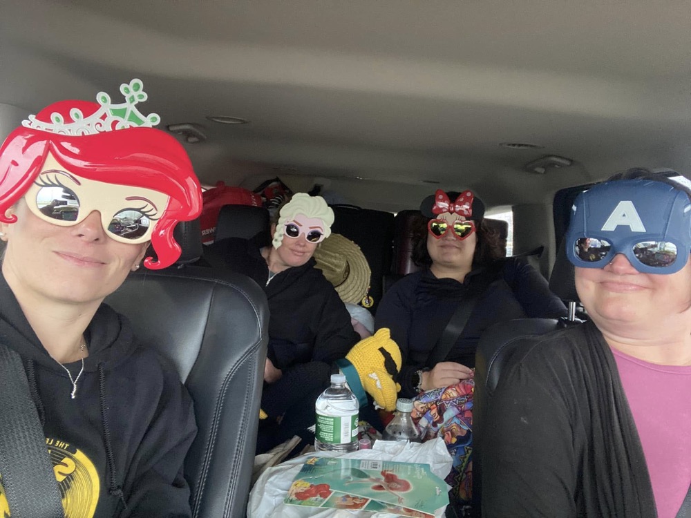 Friends wearing colourful face masks while seated together in a car