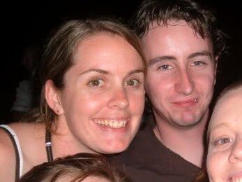 Two young friends smiling at the camera at a music concert
