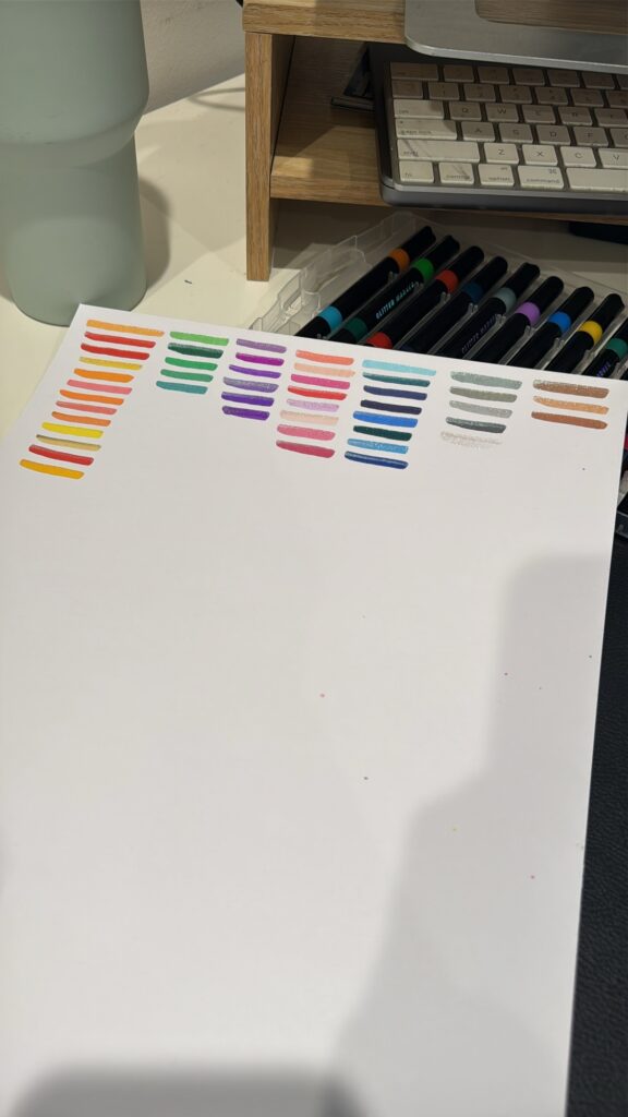 Young boy colouring in with glitter markers on cardstock pages