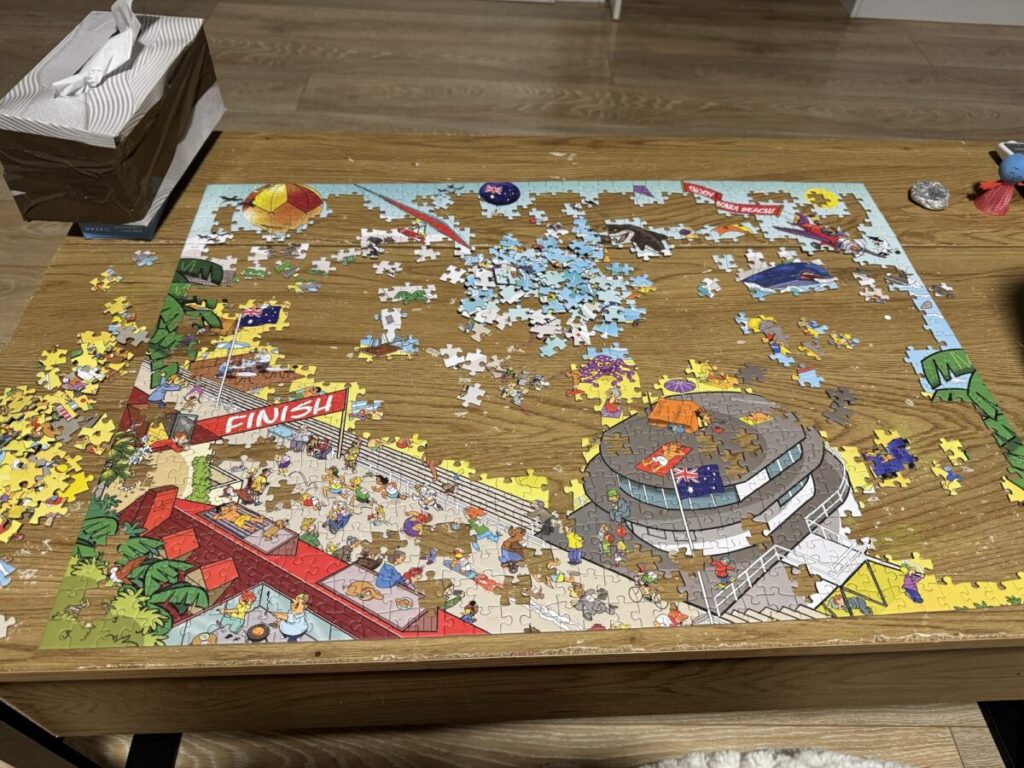 Jigsaw puzzle in progress on the table with loose pieces spread around the edges